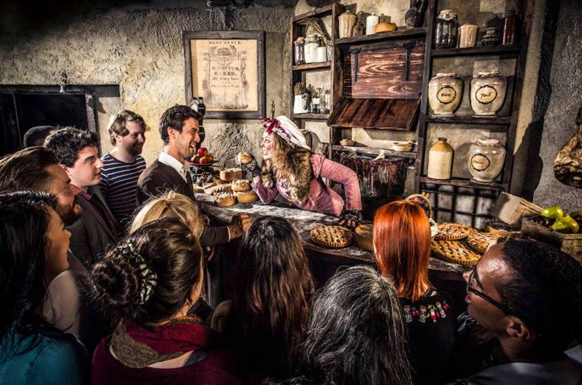 A bustling bakery scene with customers eagerly observing a woman serving baked goods at a rustic counter filled with various treats.