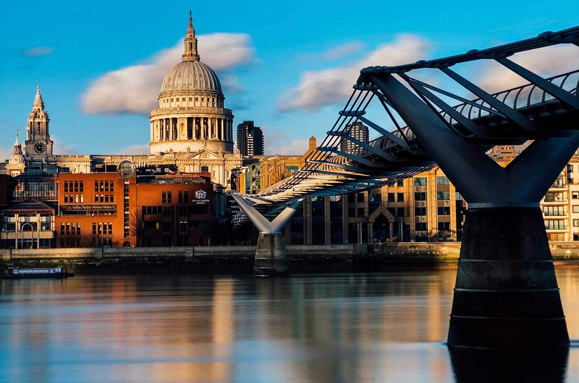 St. Paul's Cathedral stands majestically in the background, with the sleek, modern Millennium Bridge stretching across the Thames River.