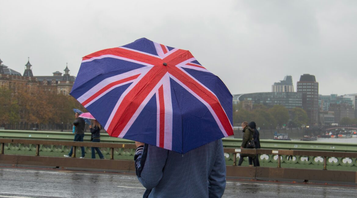 Man holding a open Union Jack umbrella on Westminster Bridge in London on a rainy day
