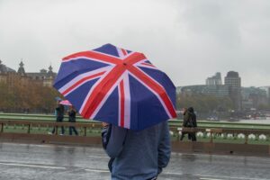 Man holding a open Union Jack umbrella on Westminster Bridge in London on a rainy day